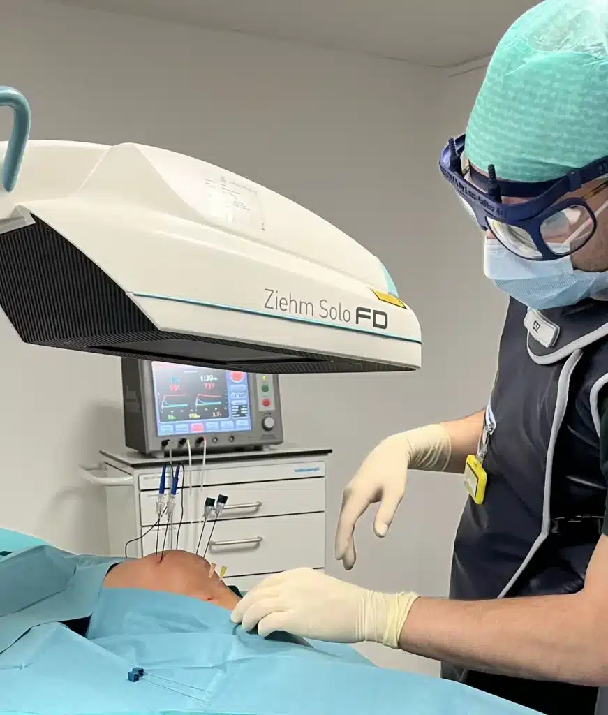 Arzt führt unter Röntgenkontrolle eine Radiofrequenz-Behandlung am Rücken eines Patienten durch.